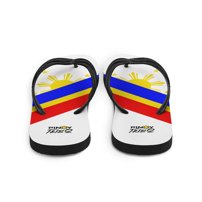 Flip flops featuring a bold Philippine flag-inspired design with diagonal blue, red, and yellow stripes, black straps, and the PINOY TRIBO™ logo printed at the heel.