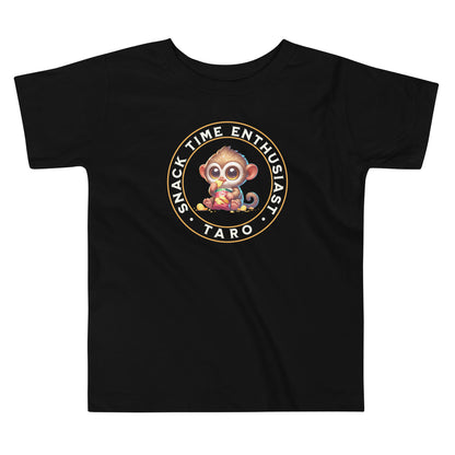 Toddler tee design featuring a cartoon tarsier named Taro eating chips from a bag with the words “Snack Time Enthusiast” in a circular badge-style layout.