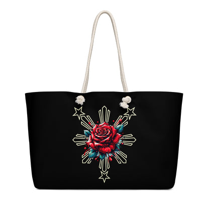 Weekender bag with a rose and sunburst three-star Filipino design on a black background with rope handles.