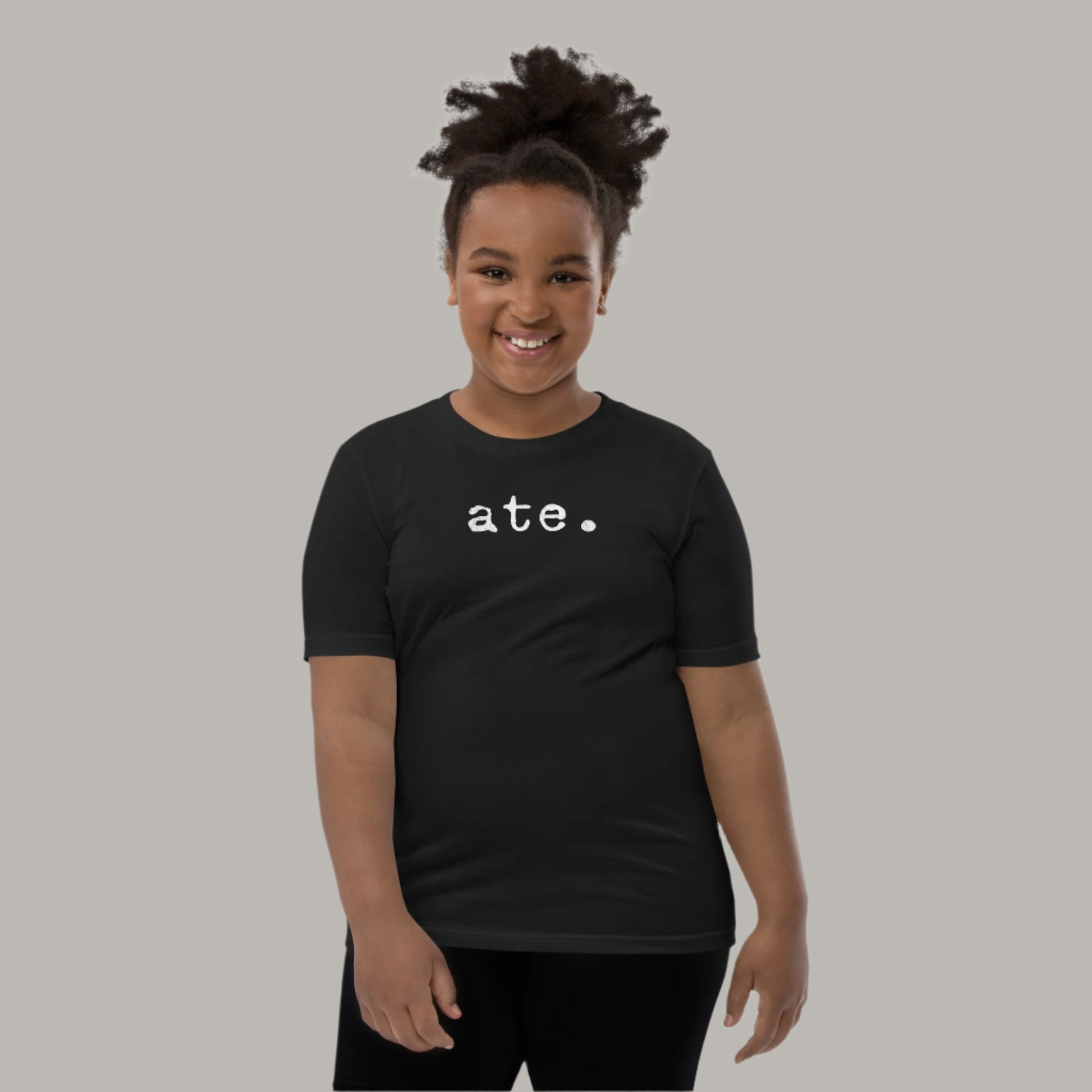 Minimalist white text “ate.” in a typewriter-style font on a youth t-shirt design.